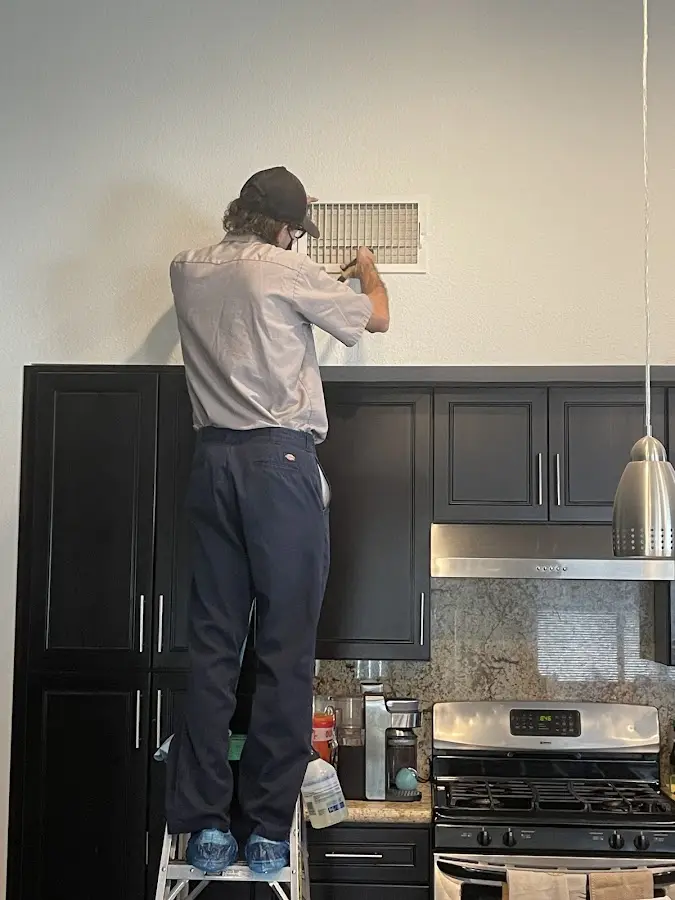 Technician inspecting an air vent during HVAC service in Westborough